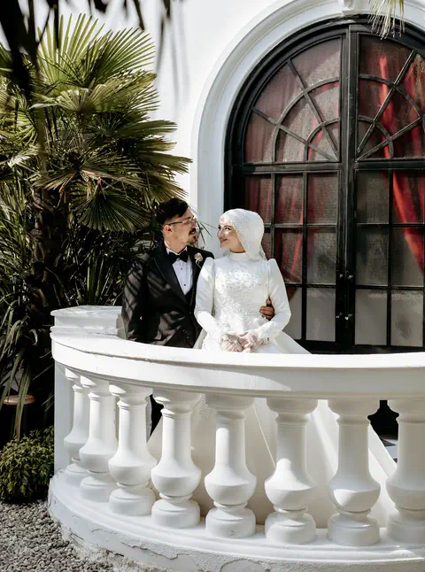 Beyaz balkonda el ele tutan gelin ve damat